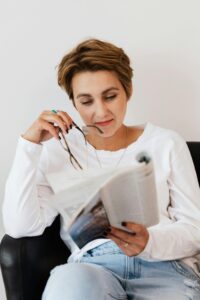 Woman Reading a Nursing Journal Article with Glasses in Hand