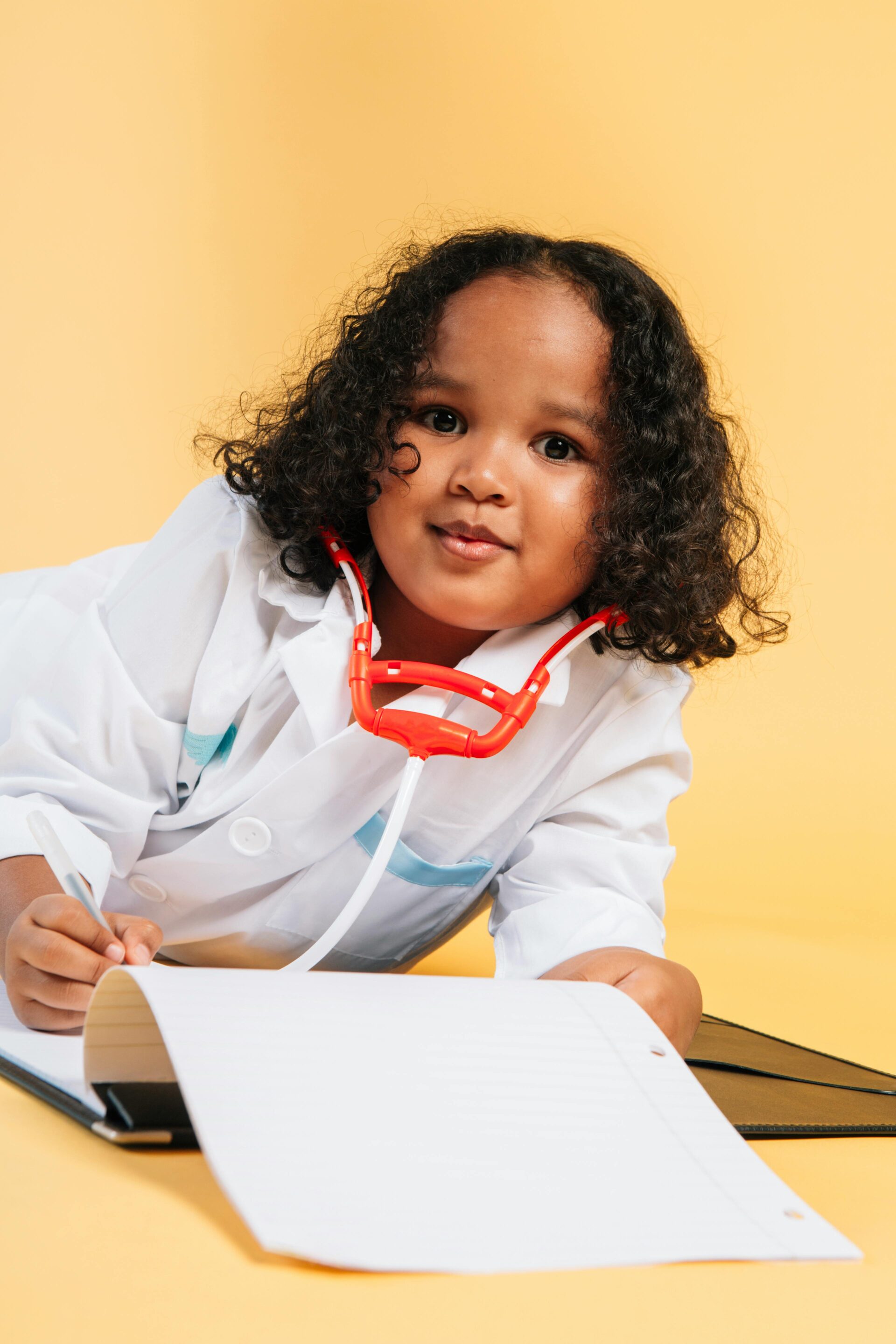 Young child dressed as a doctor writing a SOAP Note writing Service on a clipboard with a stethoscope around the neck