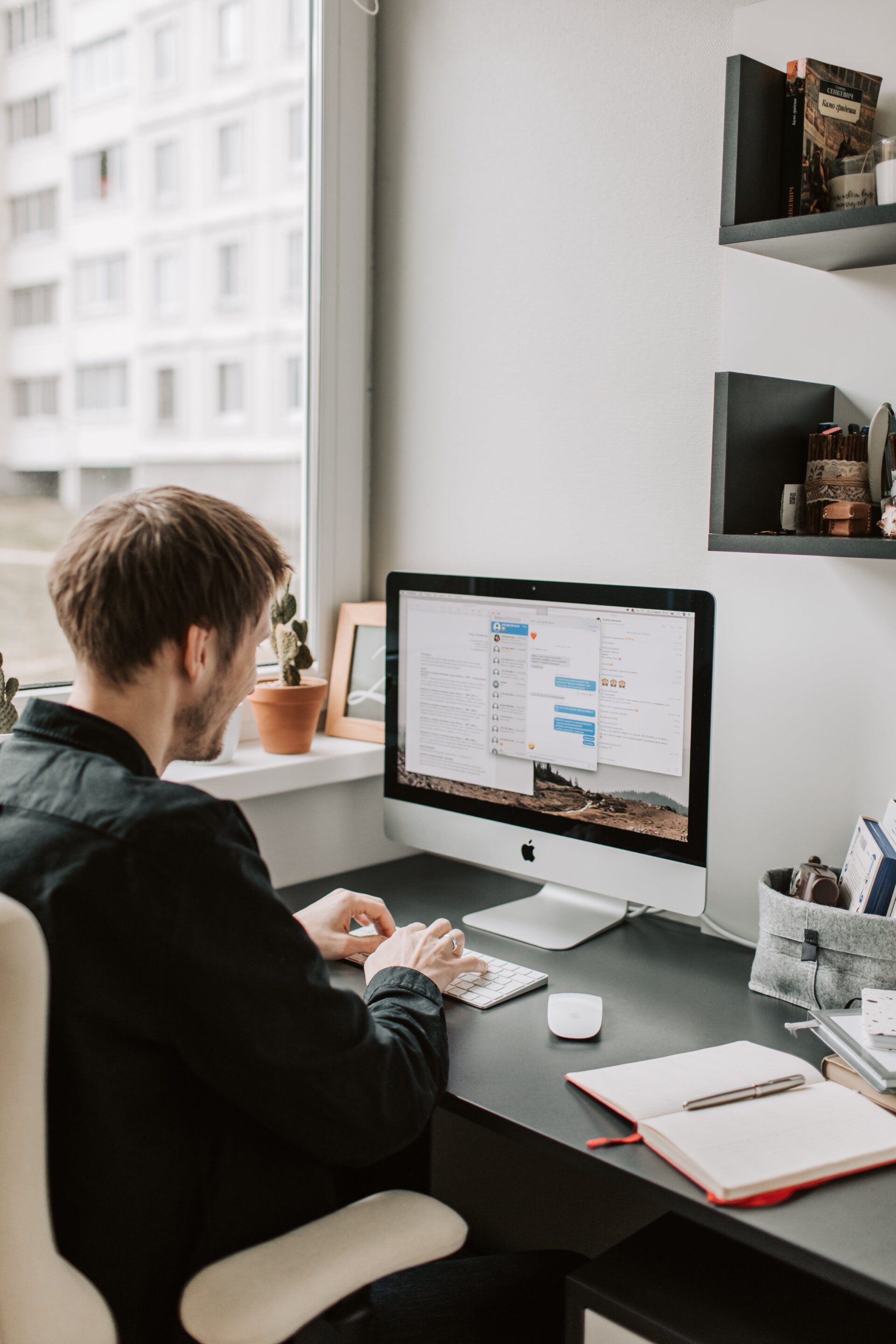 A writer working on an iMac in a well-organized home office environment