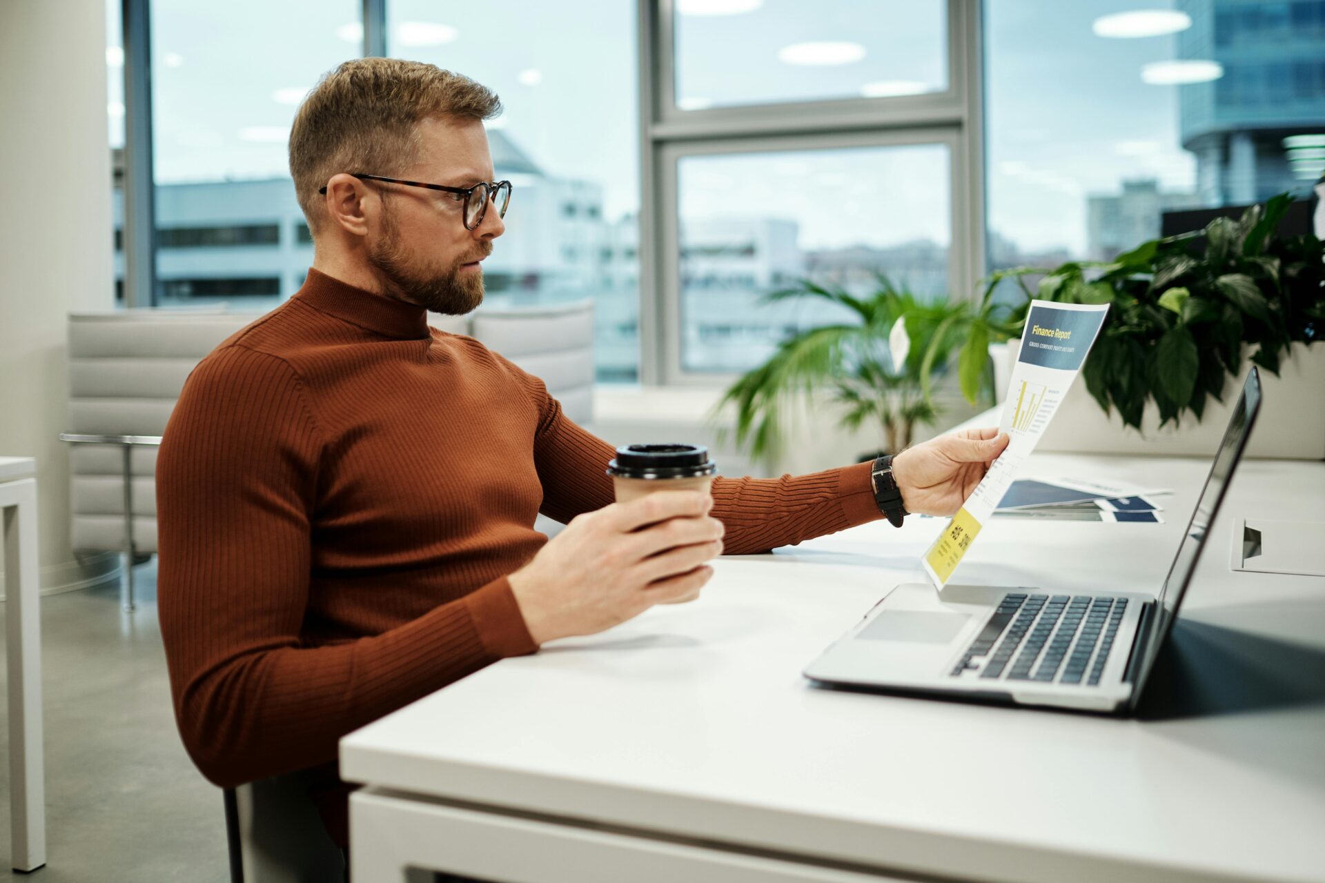 A lab assistatnt analyzing a lab report while working on a laptop in a modern office setting