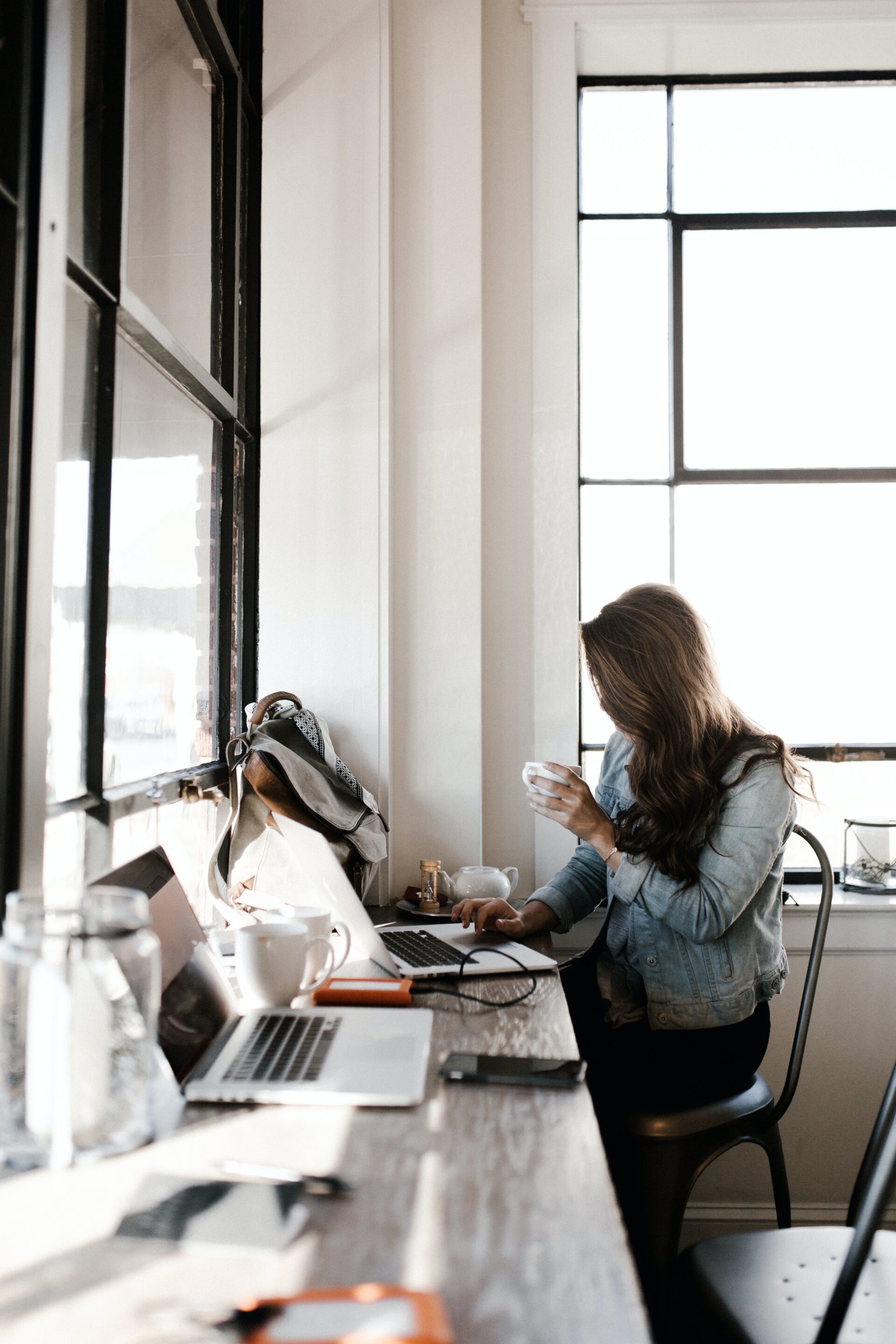 Woman working on laptop in café with coffee mug