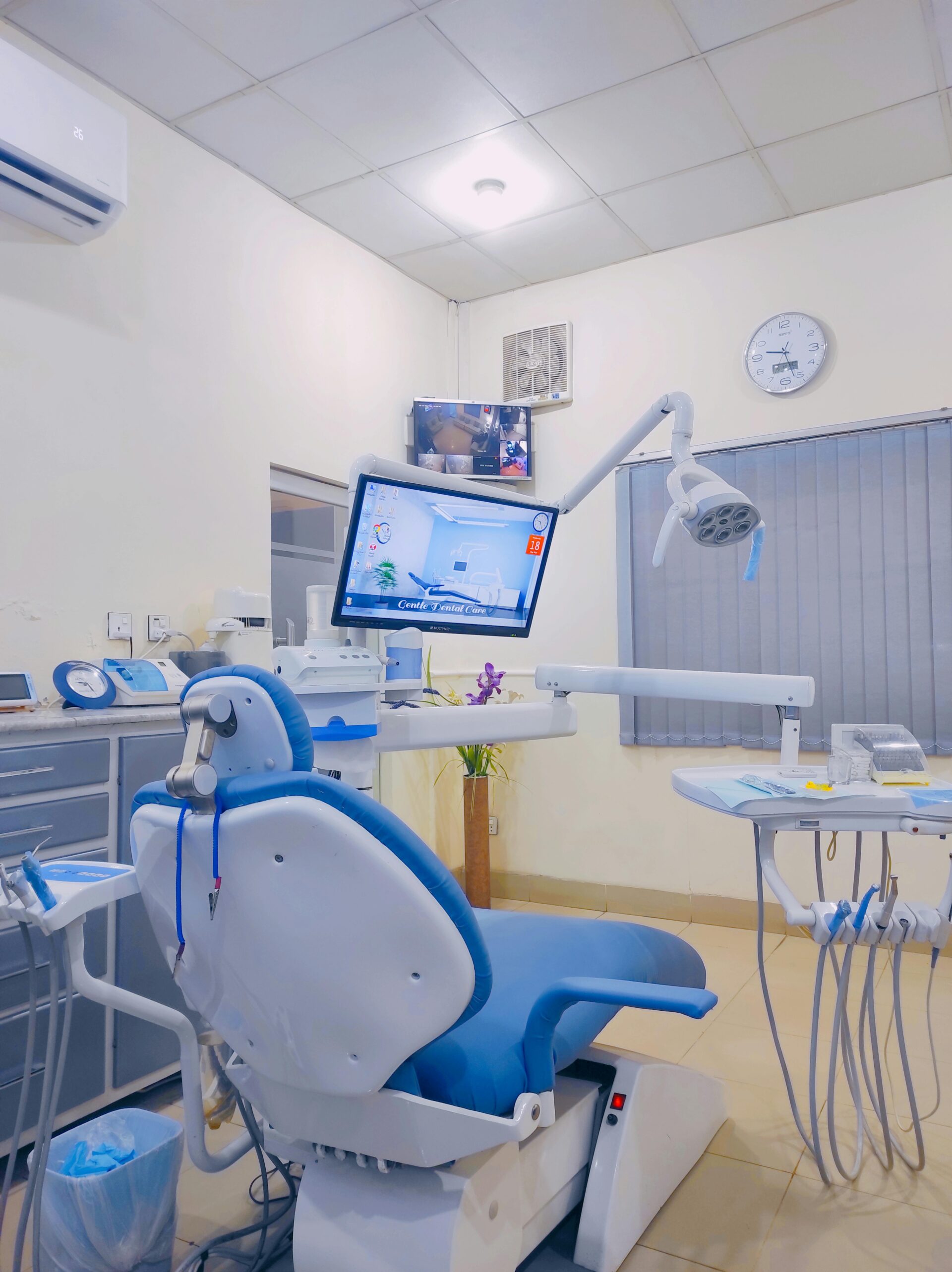 Modern dental clinic interior featuring a state-of-the-art dentist's chair with integrated technology, dental instruments, and a monitor displaying oral care information, set against a clean and professional backdrop.