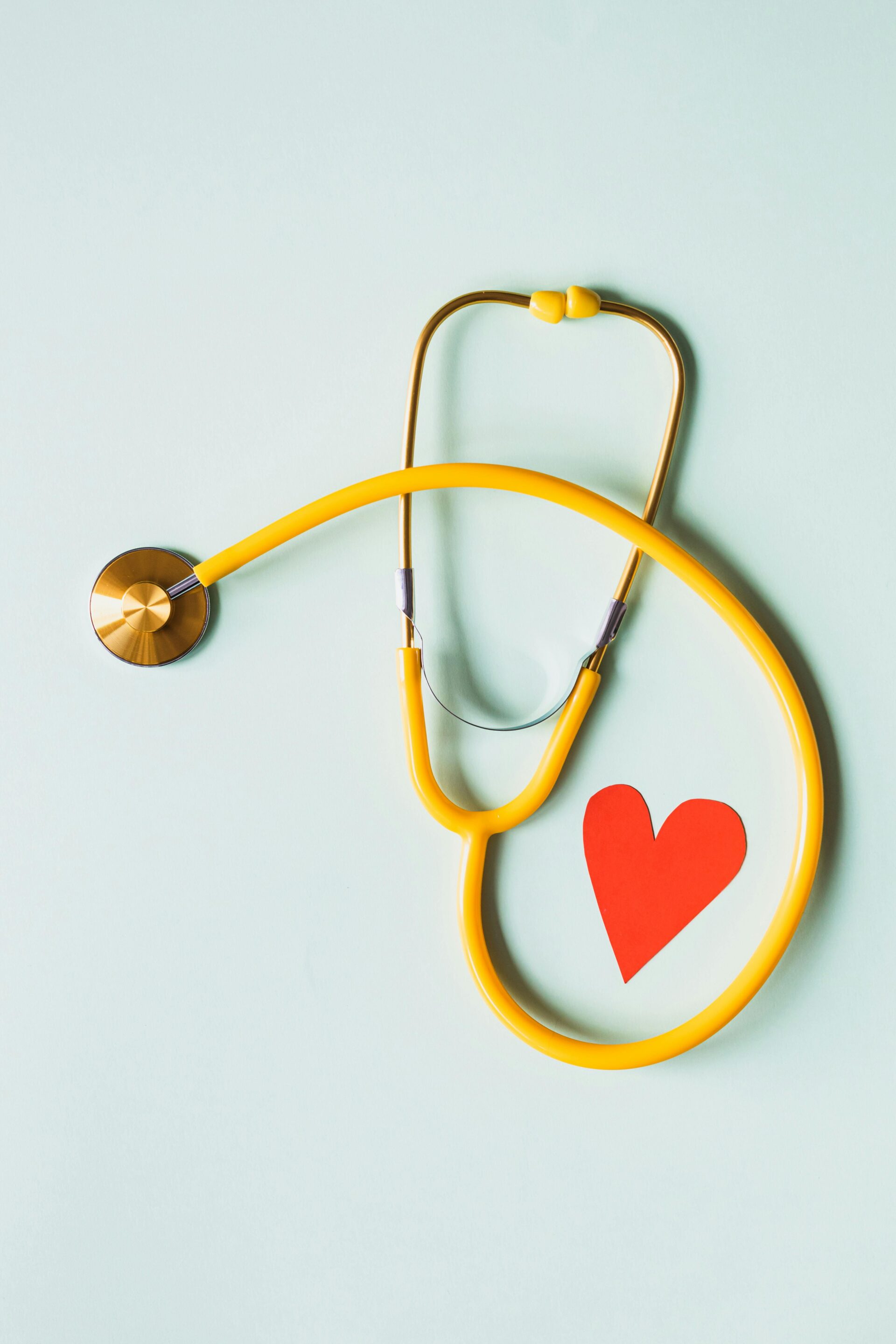 Yellow stethoscope with a red heart cutout on a light blue background, symbolizing healthcare and nursing informatics.