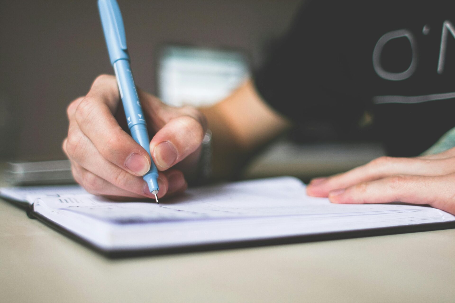 Person writing in a notebook, representing professional nursing writing service